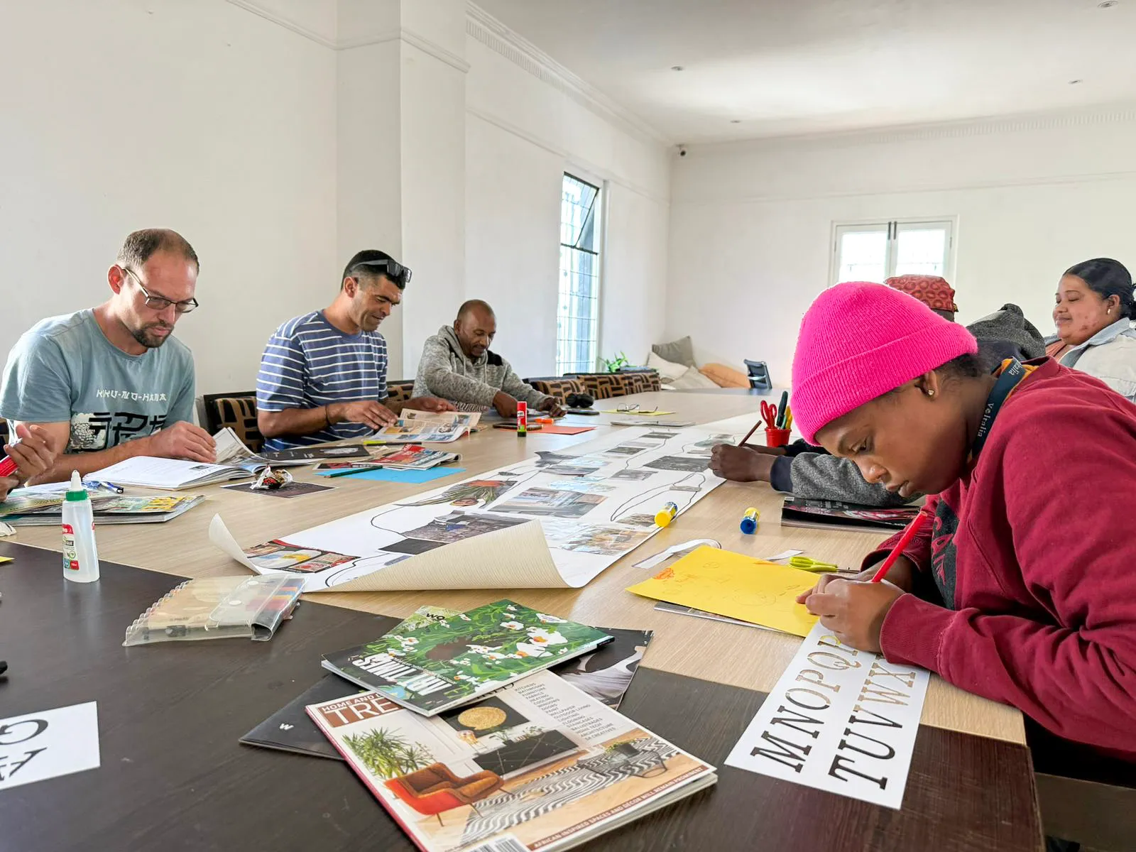 A collage workshop around a long table at The Humanity Hub